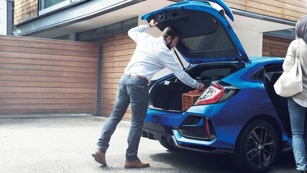 Man öppnar bagagelucka i blå Honda Civic