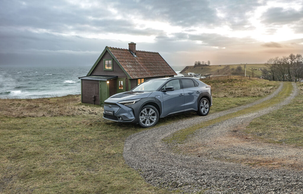Subaru Solterra parkerad vid ett hus vid havet
