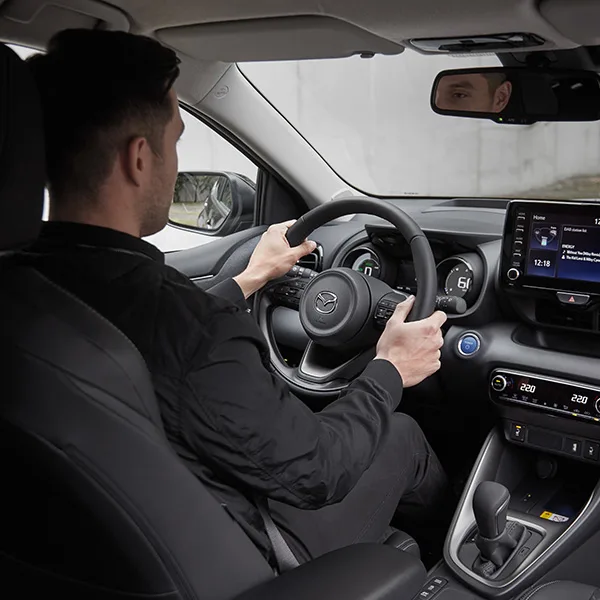 Interiörbild där en man kör en Mazda2 Hybrid