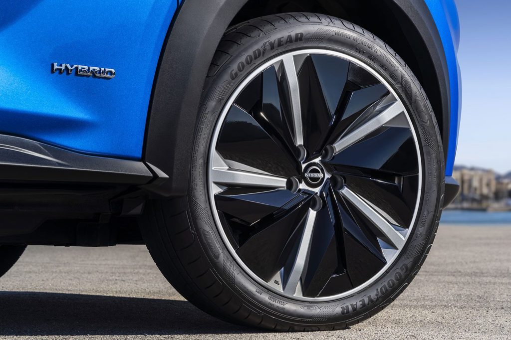 Teaserbild på Hybridemblem och hjul tillhörande kommande en blå Nissan Juke Hybrid