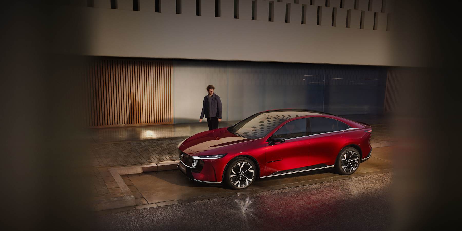 Nya MAZDA 6e elbil i röd färg och man som beundrar bilens design