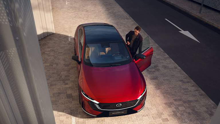 Nya MAZDA 6e elbil i röd färg med öppen dörr och man som kliver in